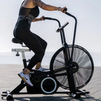 Person using an exercise bike outdoors with a clear sky background