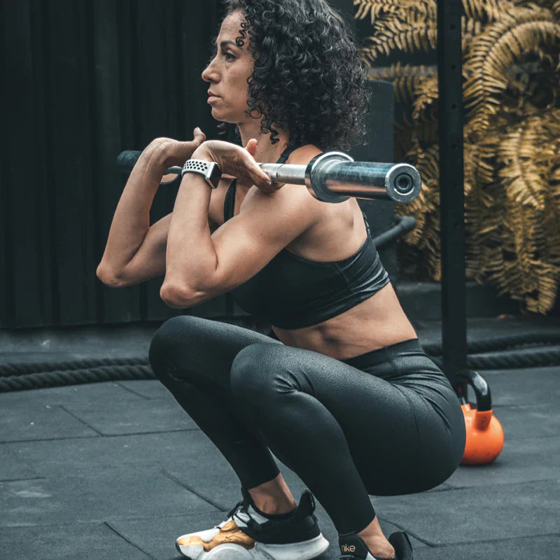 Woman performing a squat with a barbell in a gym setting
