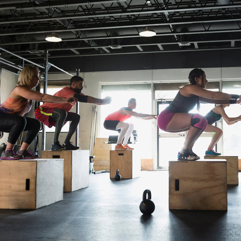 Group of people performing box jumps in a gym setting