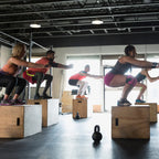 Group of people performing box jumps in a gym setting