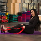 Woman exercising with resistance bands on a purple mat in a gym.