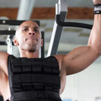 Man exercising in a gym wearing a black weight vest.