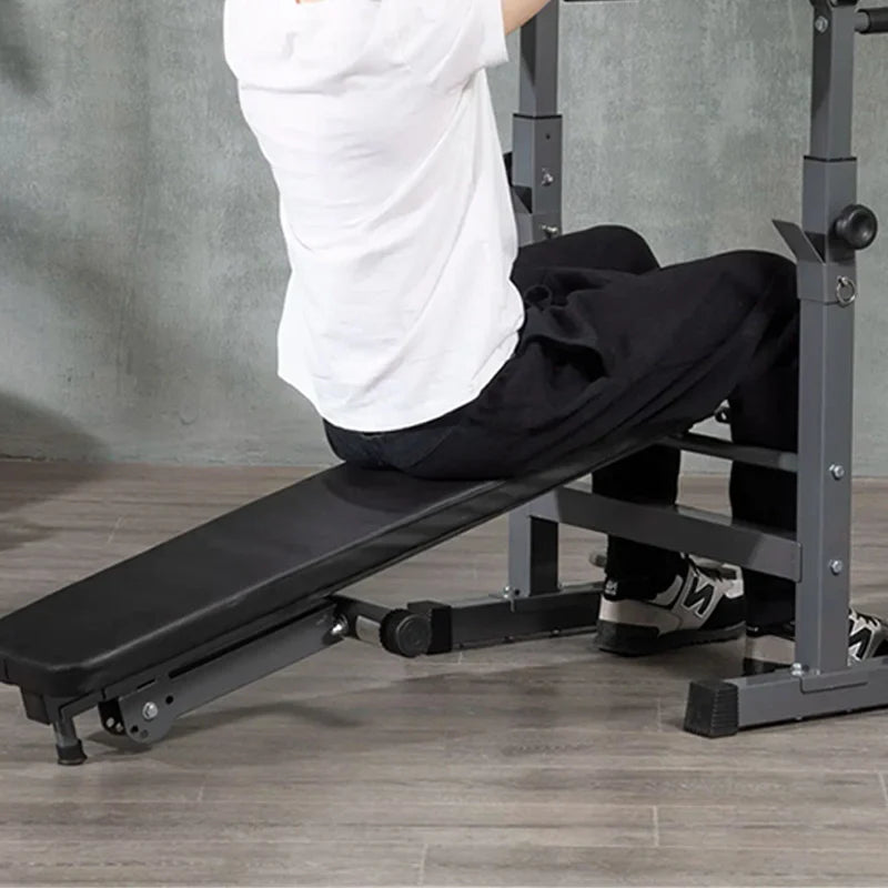 Person using a black adjustable weight bench in a home gym setting.